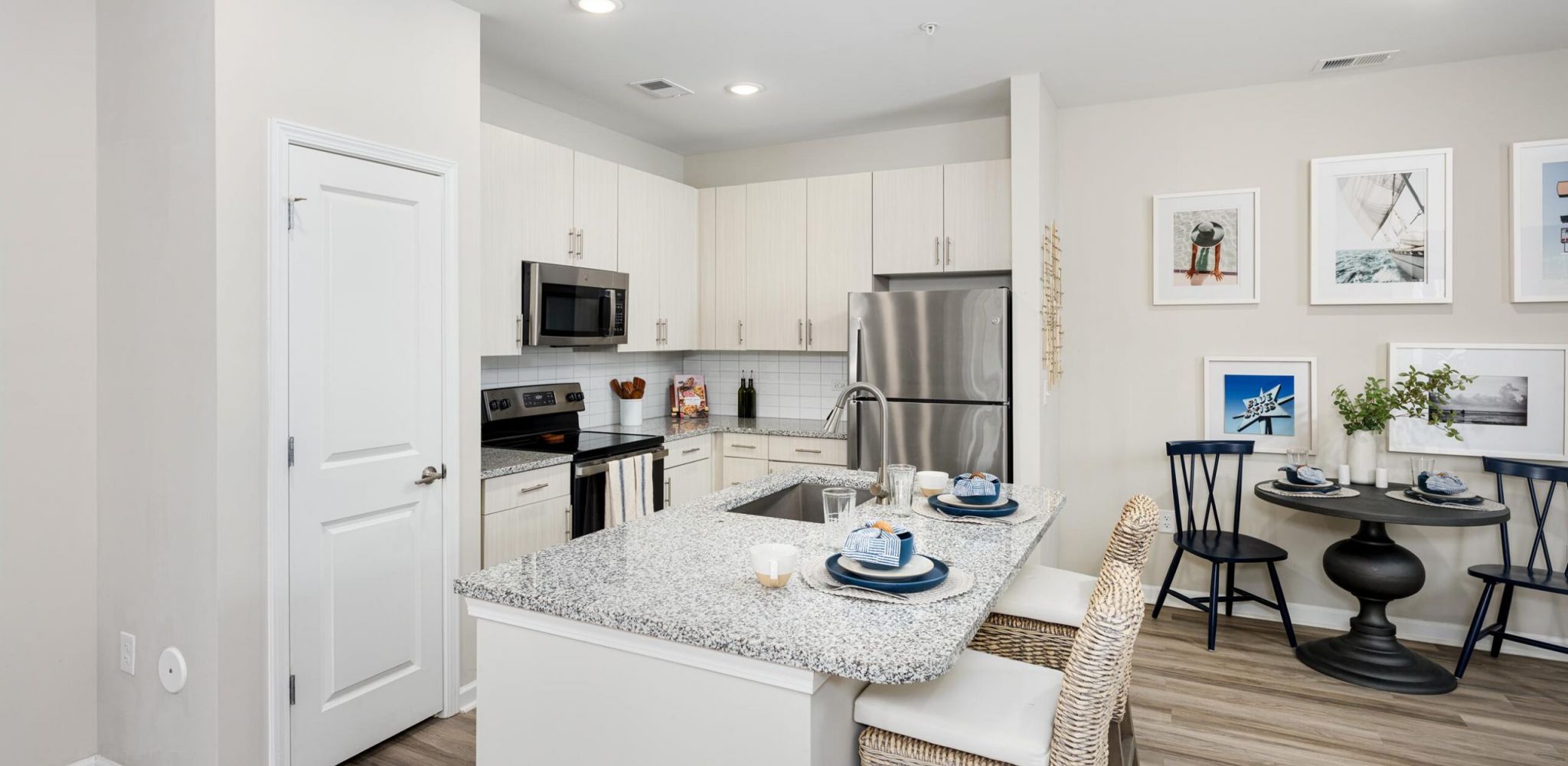 Hudson at Carolina ColoursA modern kitchen and dining area in a new apartment island with chairs, stainless steel appliances, and a large sink